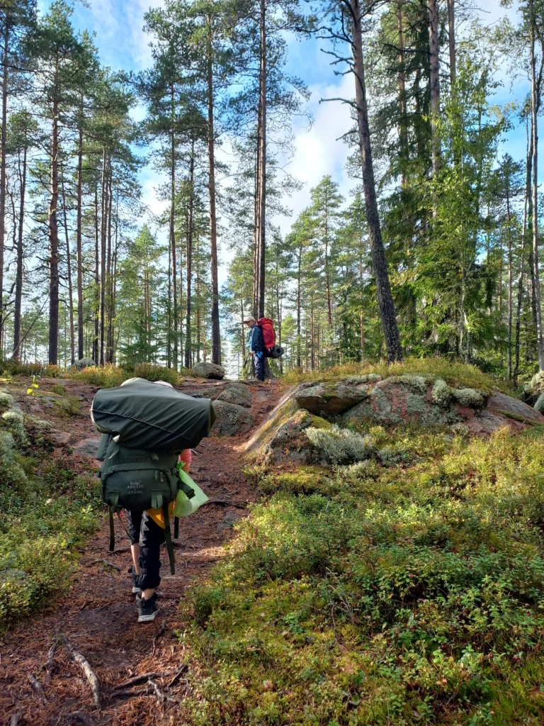 Poika seisoo mäen päällä, ja tyttö kiipeää mäkeä ylös